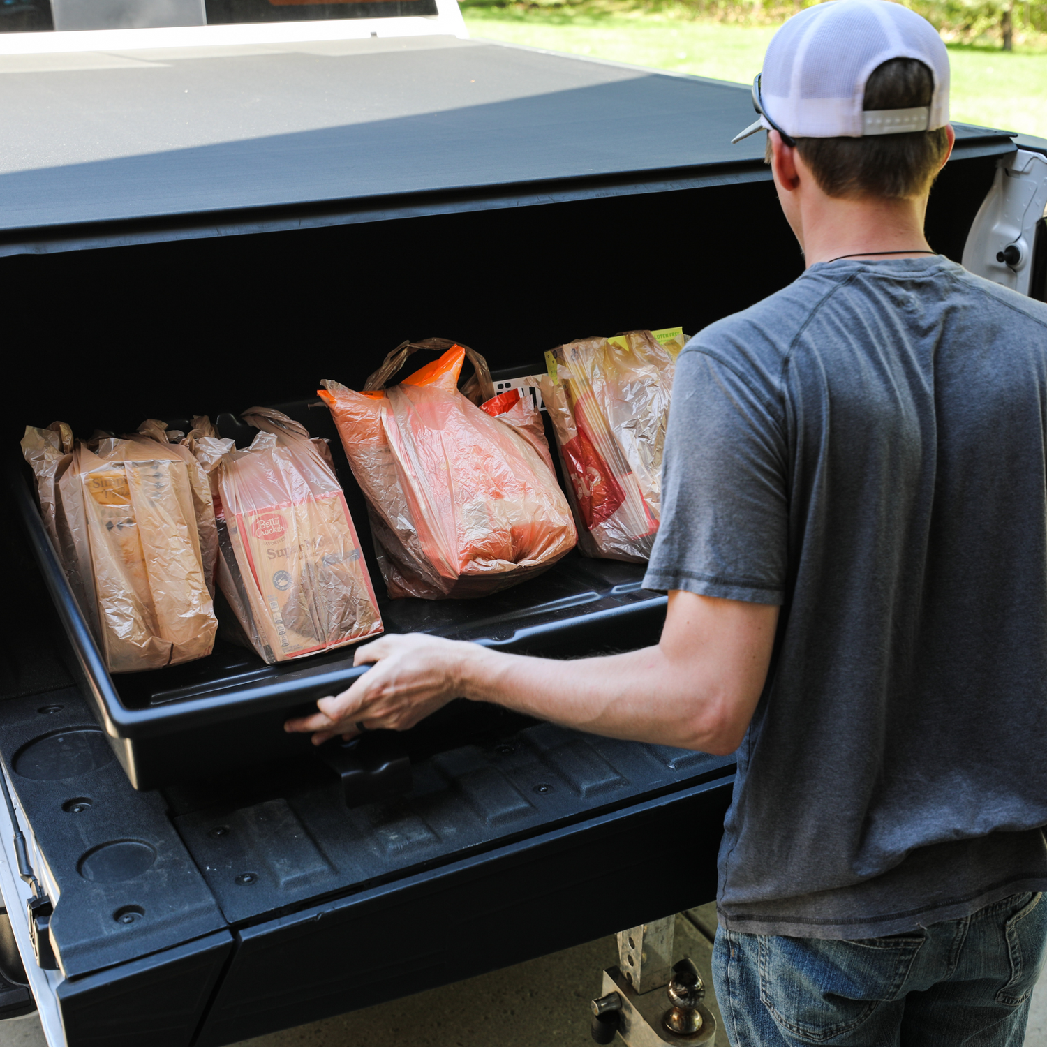 Used to navigate to the CargoStop product listing. Photo shows a man using the cargostop truck bed organizer filled with groceries.