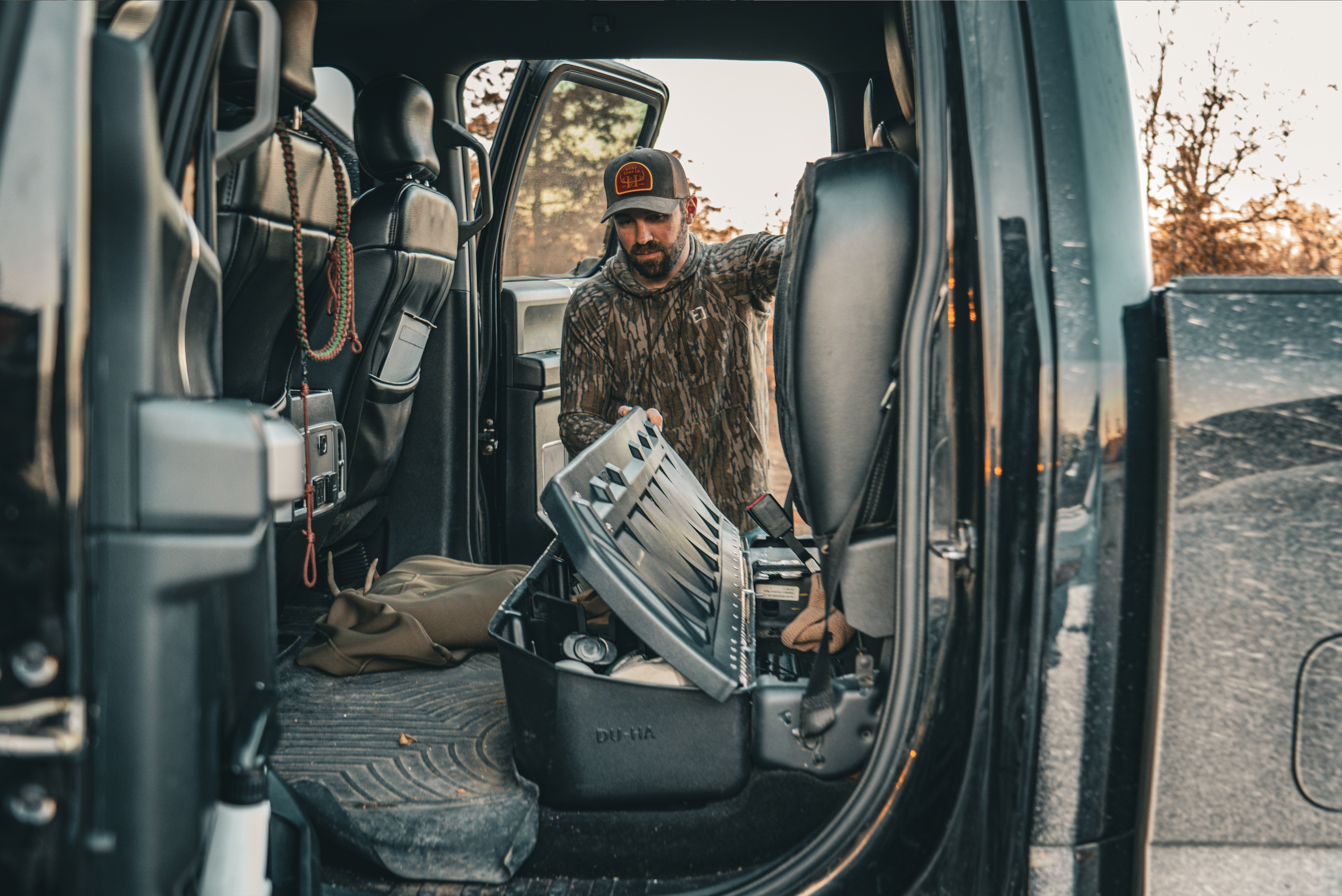 Image used to navigate to a page with truck accessory categories. Shows a man using the lockable under seat in the back of a truck.