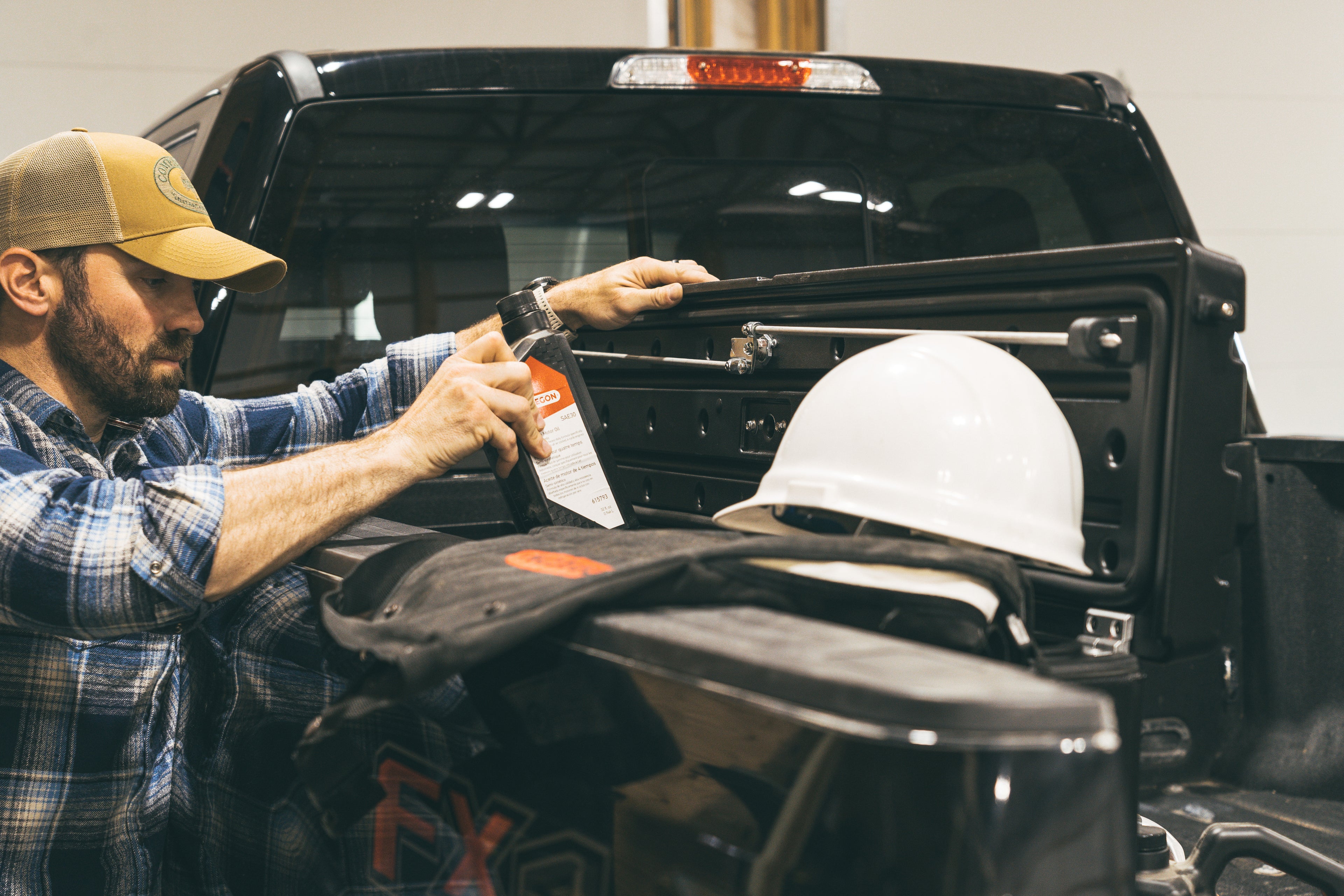 Shows a man grabbing chain oil out of his side tool box.