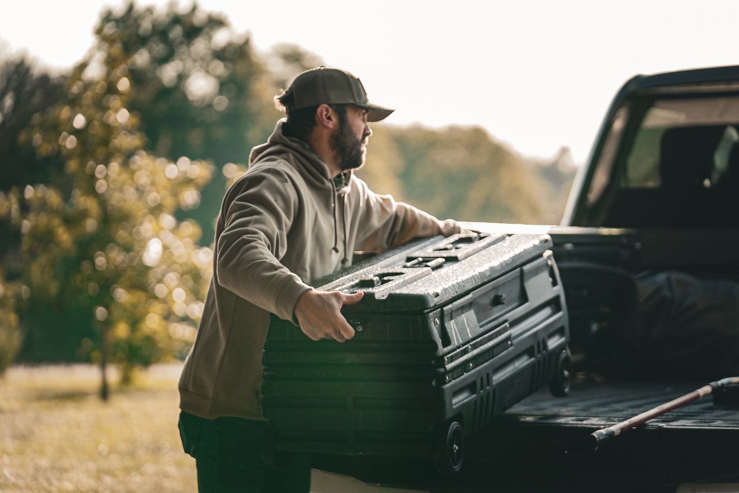 This photo is linked to the Squad Box collection page. The image shows a man lifting a squad box into the bed of his truck.